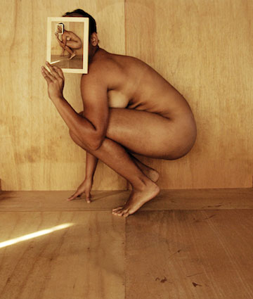 Photograph of a crouching nude figure holding the same photograph over their head.
