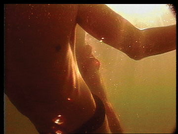 Still depicting a close up on a figure in the water, backlit.