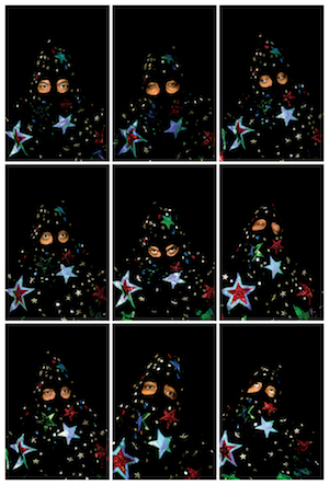 Nine photographs of a figure wearing a black hood painted with multi-colored stars against a black backdrop.