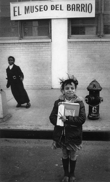 Black and white photograph showing two kids below a sign that reads, "El museo del barrio