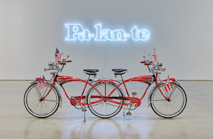 Photograph of a bicycle in front of a neon sign with the Spanish text, "Forward."
