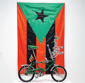 Photograph of a bicycle in front of a flag.