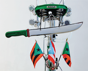 Photograph of a bike decked with flags and a knife.